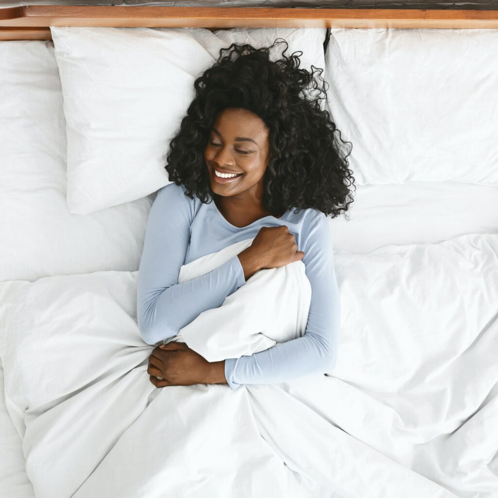 Top view of smiling woman waking up in her bed