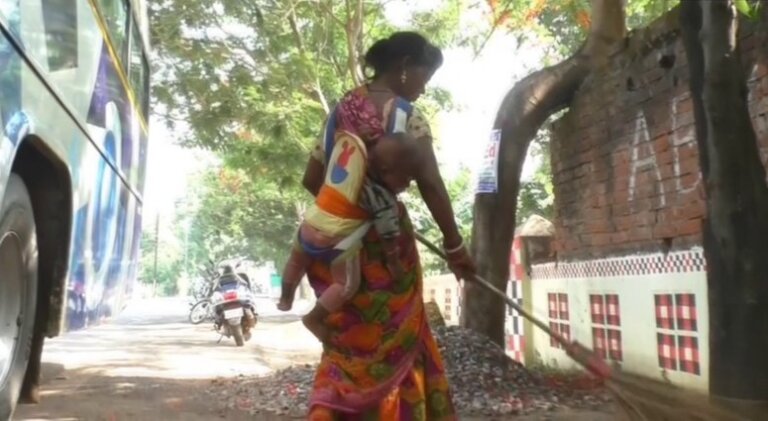 දරුවා පිටේ බැඳන් වීදි පිරිසිදු කරනා දිරිය මව දරුවා පිටේ බැඳන් වීදි පිරිසිදු කරනා දිරිය මව