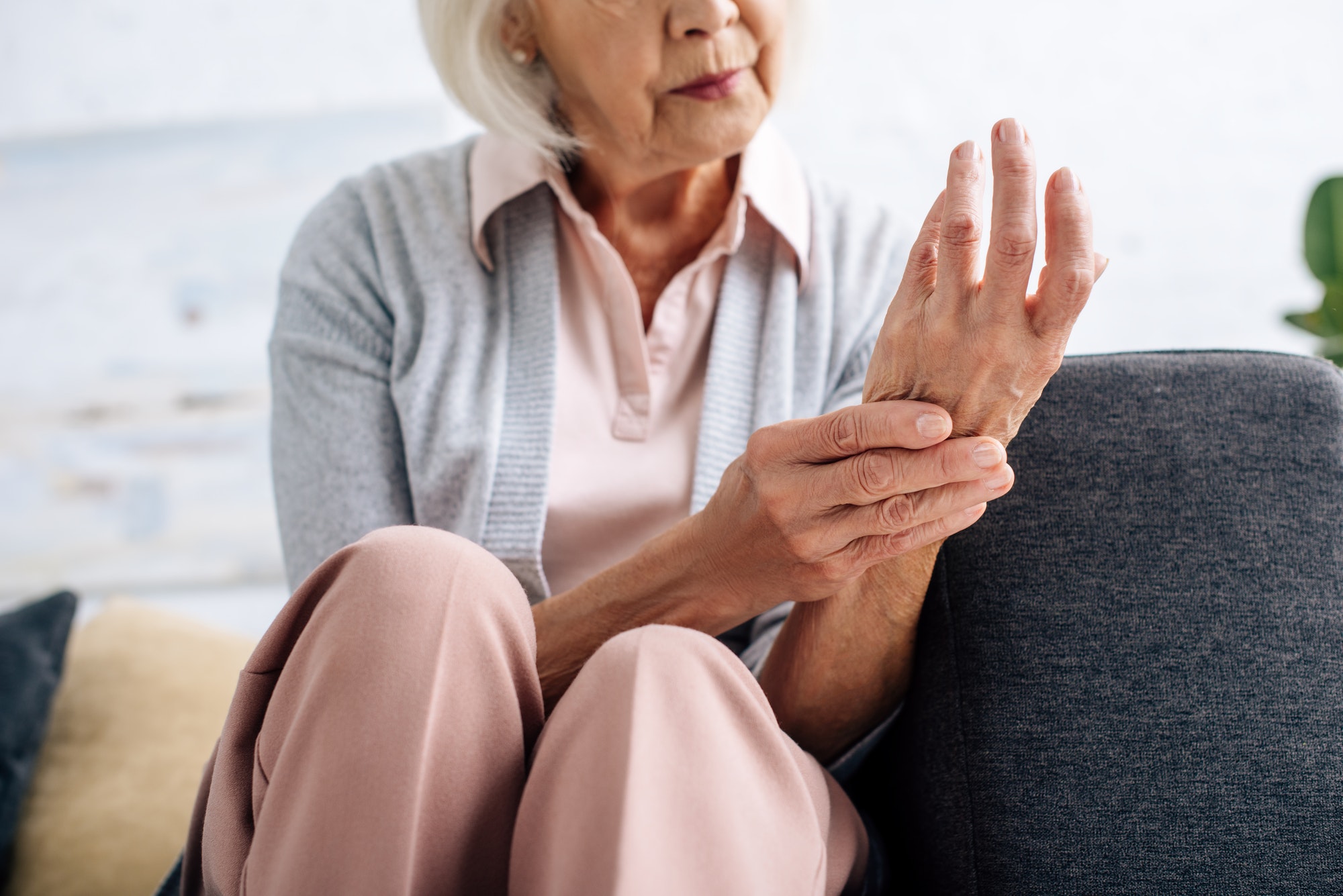 cropped view of senior woman having Arthritis in hand in apartment